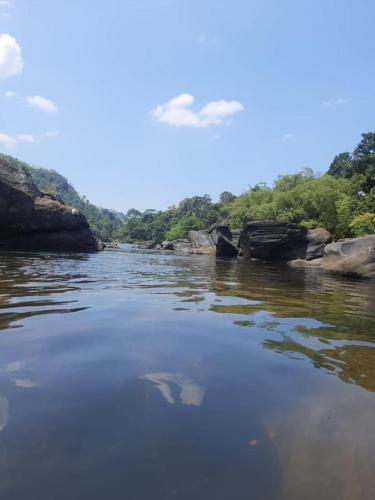 a river with rocks and trees in the background at Kit Cott Resort and Retreat in Teligama