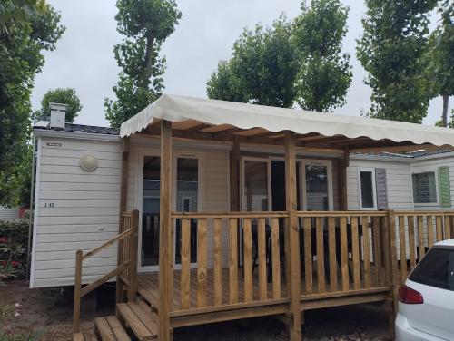 a tiny house with a porch and an awning at Camping la jasse sables du midi 4 étoiles in Valras-Plage
