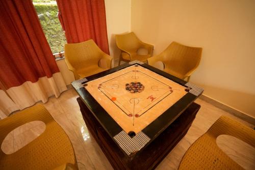 a table with a clock on it in a room with chairs at Chirping Hills Resort,Bhimtal in Bhīm Tāl