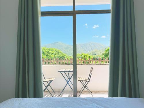 a bedroom with a view of a balcony with a table and chairs at Cloud Tree Inn Boutique Guesthouse XiChong DaPeng ShenZhen 深圳大鹏西涌云树里民宿Yun Shu Li in Shenzhen