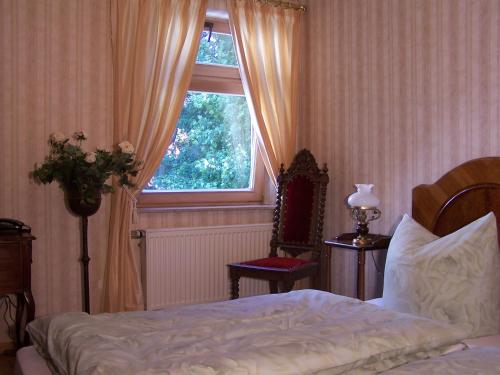 a bedroom with a bed and a window and a chair at Hotel Villa Herzog in Dresden