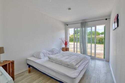 une chambre blanche avec un lit et une grande fenêtre dans l'établissement Liberté Oléron - Belle maison proche de la plage, à Grand-Village-Plage