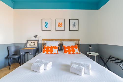 une chambre avec un grand lit blanc avec des oreillers orange dans l'établissement Le Skyline - Apt climatisé avec terrasse Marseille, à Marseille