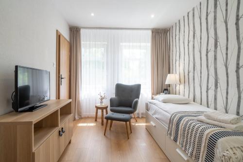 a bedroom with a bed and a chair and a television at Ośrodek Wypoczynkowy Zacisze in Śliwice
