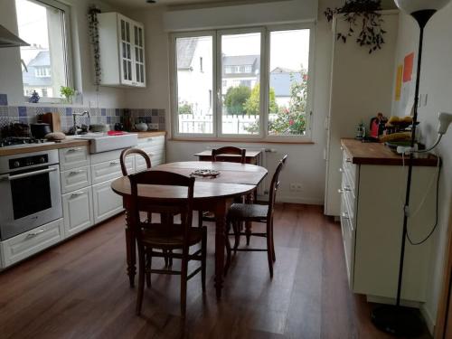 une cuisine avec une table et des chaises dans l'établissement Maison des fontaines, calme spacieuse avec grand jardin, à Lannion