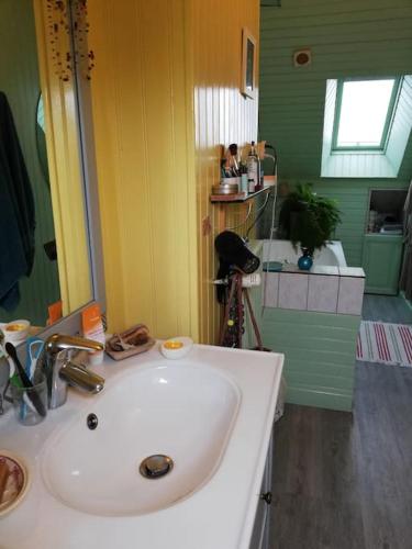 La salle de bains est pourvue d'un lavabo blanc. dans l'établissement Maison des fontaines, calme spacieuse avec grand jardin, à Lannion