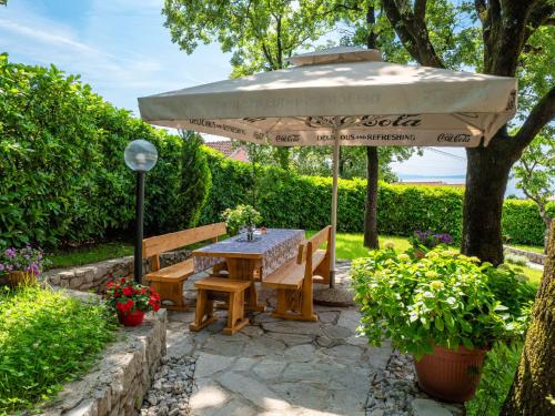 a table and bench under an umbrella in a garden at Apartment Marijo by Interhome in Matulji