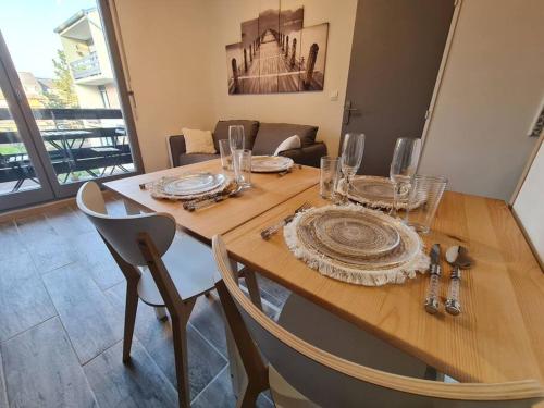 une table en bois avec des assiettes et des verres au-dessus dans l'établissement Convivialité agréable séjour au calme, à Cabourg