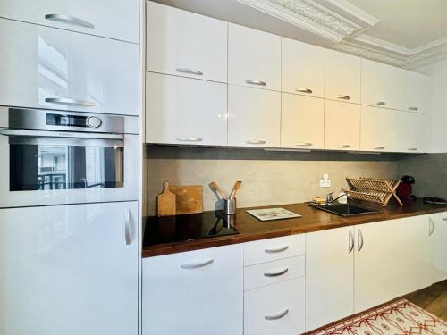 une cuisine avec des placards blancs et un comptoir dans l'établissement Charming Apartment Paris - Rentaway BnB, à Paris