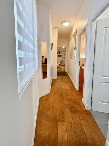 - un couloir avec des murs blancs et du parquet dans l'établissement Charming Apartment Paris - Rentaway BnB, à Paris