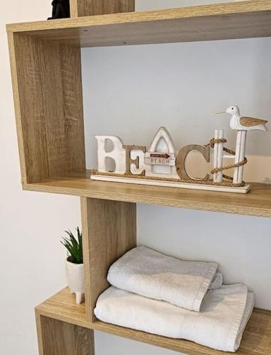 une étagère en bois avec des serviettes et un panneau indiquant bébé dans l'établissement Convivialité agréable séjour au calme, à Cabourg