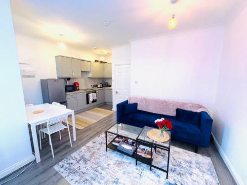 a living room with a blue couch and a table at A modern 2 bedroom seaside apartment in Hastings