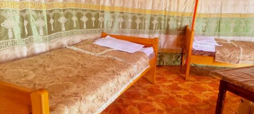 a bedroom with two beds and a table in it at MONKHSUURI GUESTHOUSE in Harhorin