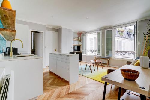 une cuisine avec des armoires blanches et un salon dans l'établissement SaintGermain Sojourn - Charming 2 bedroom in the Rive Gauche, à Paris
