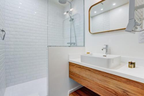 une salle de bain blanche avec un lavabo et un miroir dans l'établissement SaintGermain Sojourn - Charming 2 bedroom in the Rive Gauche, à Paris