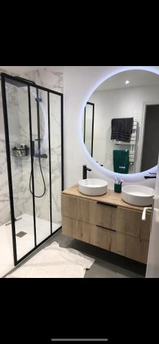 une salle de bain avec deux lavabos et un grand miroir dans l'établissement Appartement Lumineux Anglet, à Anglet