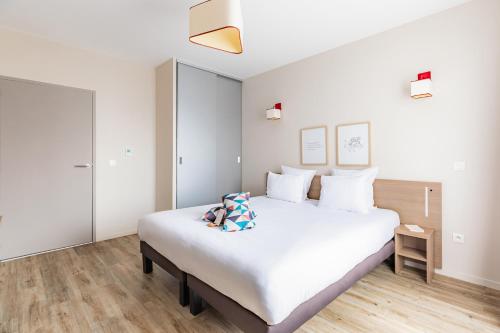 a bedroom with a large white bed with white pillows at Appart'City Confort Cherbourg in Cherbourg en Cotentin