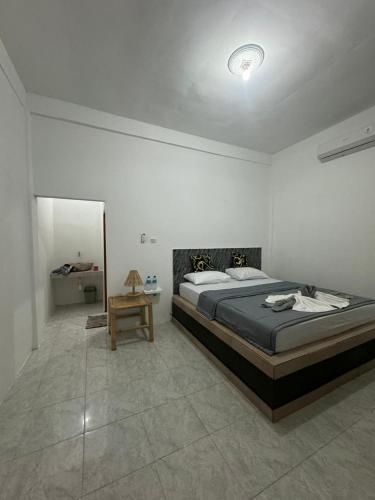 a bedroom with a large bed and a table at Black Sweet Homestay Dua in Gili Islands