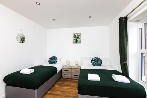 two beds in a room with white walls at City-Center 2-Bedroom Apartment near Train Station in Dewsbury
