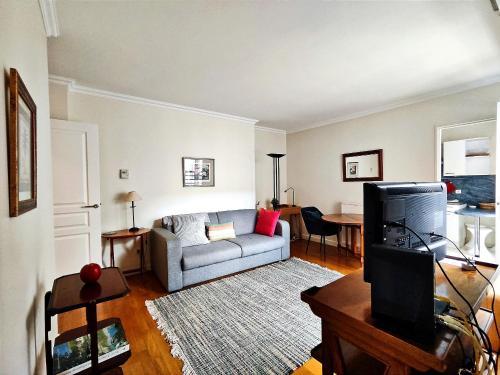 un salon avec un canapé et une télévision dans l'établissement Passage Doisy - Paris 17, à Paris