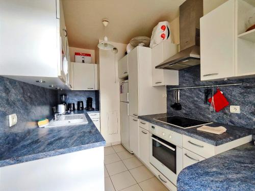 une cuisine avec des armoires blanches et un évier dans l'établissement Passage Doisy - Paris 17, à Paris