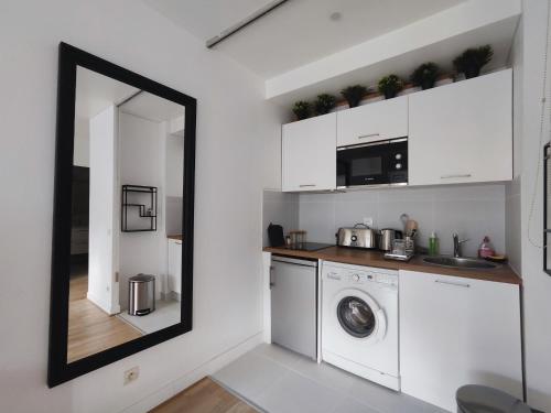 une buanderie avec lave-linge, sèche-linge et un miroir dans l'établissement Rue de Berri - Paris 8, à Paris