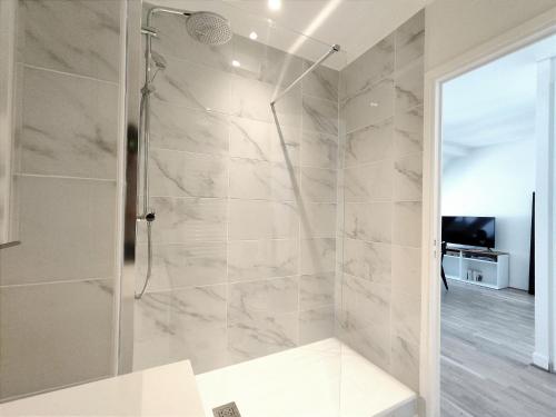 une douche avec une porte vitrée dans une salle de bain dans l'établissement Rue de Berri - Paris 8, à Paris