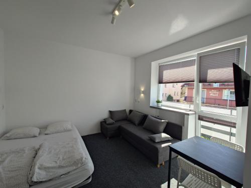 a bedroom with a bed and a couch and a window at Marynarska 57 in Darlowko