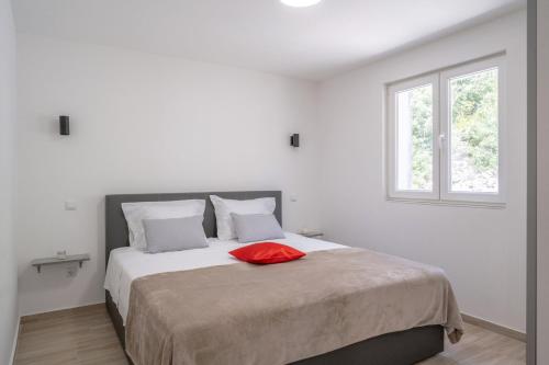 a bedroom with a bed with a red pillow on it at Apartments dida Ante in Blato