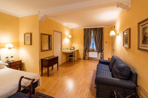a hotel room with a bed and a couch and a desk at Phi Hotel Canalgrande in Modena