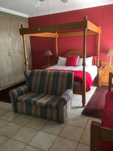 Un dormitorio con una cama con dosel y un sofá. en Birrea Guest house, en Polokwane