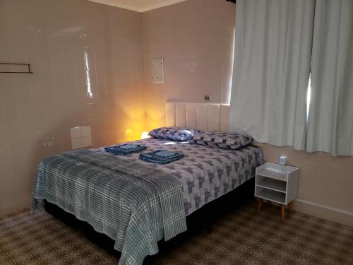 a bedroom with a bed with a blanket and a window at Pousada Monte Gerizim in Sao Paulo