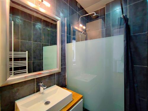 une salle de bain avec un lavabo et une douche avec un miroir dans l'établissement Rue Eugene Delacroix - Paris 16, à Paris