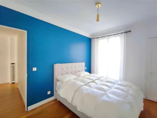 - une chambre avec un mur bleu et un lit blanc dans l'établissement Rue Eugene Delacroix - Paris 16, à Paris