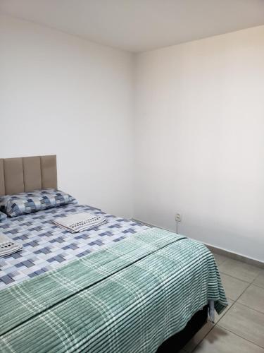 a bedroom with a bed with a green and white blanket at Pousada Monte Gerizim in Sao Paulo