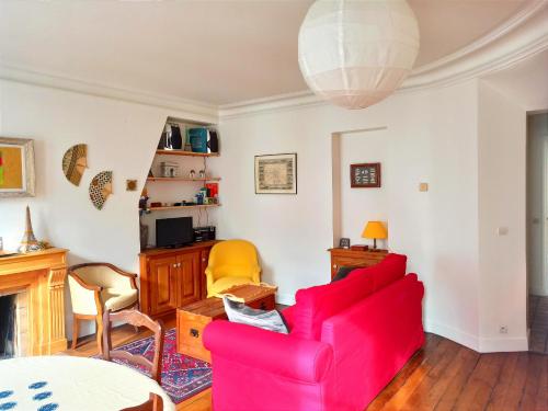 un salon avec un canapé rouge et une table dans l'établissement Rue Poncelet - Paris 17, à Paris