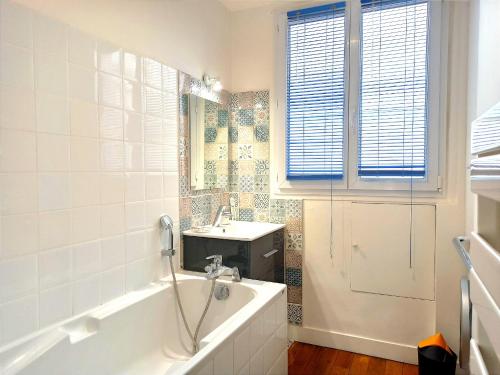 une salle de bain blanche avec une baignoire et un lavabo dans l'établissement Rue Poncelet - Paris 17, à Paris
