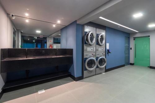 a laundry room with three washing machines and a sink at Loft próximo a Vila Germânica e FURB com vaga. in Blumenau