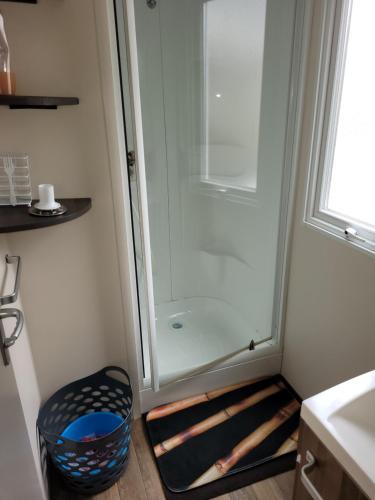 une douche avec une porte vitrée dans une salle de bain dans l'établissement Mobil home 6/8 pers Les Dunes de Contis, à Saint-Julien-en-Born
