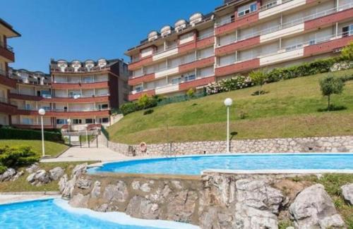 a swimming pool in front of a large building at ApartamentoDJ in Suances