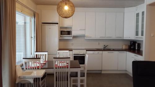 a kitchen with white cabinets and a table and chairs at Apartment Marta in Vuokatti