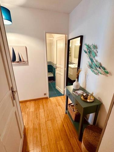 - un couloir avec une table et un miroir dans la chambre dans l'établissement L'Escapade Deauvillaise, T2 en plein coeur de la ville, à Deauville