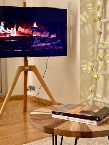 un téléviseur sur un support avec un ordinateur portable sur une table dans l'établissement L'Escapade Deauvillaise, T2 en plein coeur de la ville, à Deauville