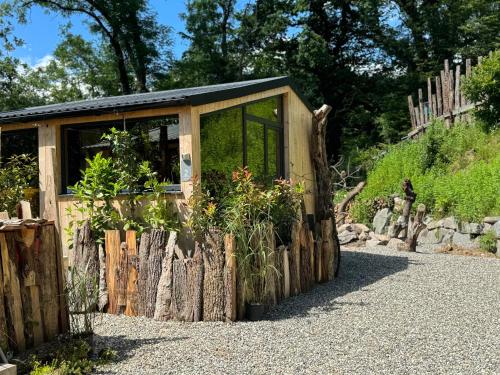 a small greenhouse with plants in it next to a fence at Domaine des Constellations - Tiny Houses & Bains Nordiques in Orbey