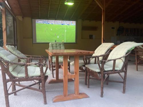 a wooden table and chairs with a soccer game on a screen at Sirius Guest House in Sinemorets