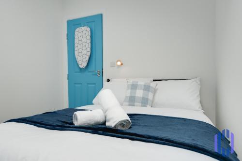 a bedroom with a blue door and a bed with towels at Santorini Blues by CEFAS - Free Parking - Bungalow - Near Airport in Manchester