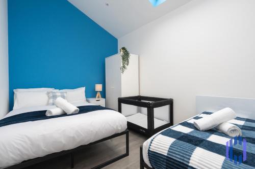 a bedroom with two beds and a blue wall at Santorini Blues by CEFAS - Free Parking - Bungalow - Near Airport in Manchester