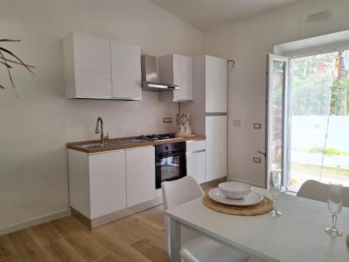 a kitchen with white cabinets and a table and a sink at Holiday House in Villa Beatrice in Porto Istana