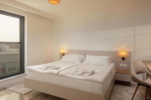 a white bedroom with a bed with towels on it at SeeSea Hotel in Vodice