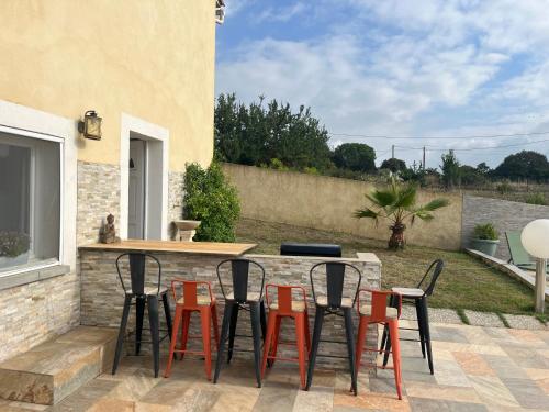 a patio with orange and black chairs and a table at Villa Héliopolis in Ventiseri